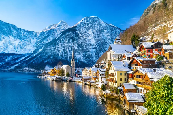 Kış aylarında mavi gökyüzü ve bulutlar ile güzel bir soğuk güneşli günde geleneksel yolcu gemisi ile Alpler 'de ünlü Hallstatt Lakeside kasabasının klasik kartpostal görünümü, Avusturya