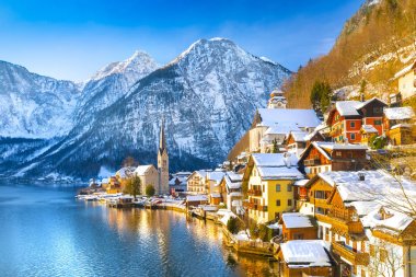 Kış aylarında mavi gökyüzü ve bulutlar ile güzel bir soğuk güneşli günde geleneksel yolcu gemisi ile Alpler 'de ünlü Hallstatt Lakeside kasabasının klasik kartpostal görünümü, Avusturya