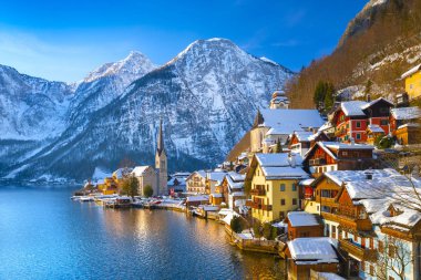 Kış aylarında mavi gökyüzü ve bulutlar ile güzel bir soğuk güneşli günde geleneksel yolcu gemisi ile Alpler 'de ünlü Hallstatt Lakeside kasabasının klasik kartpostal görünümü, Avusturya