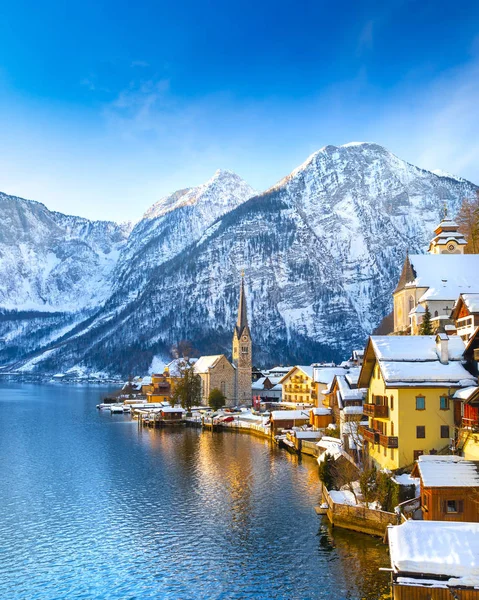 Kış aylarında mavi gökyüzü ve bulutlar ile güzel bir soğuk güneşli günde geleneksel yolcu gemisi ile Alpler 'de ünlü Hallstatt Lakeside kasabasının klasik kartpostal görünümü, Avusturya