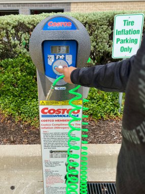 Frisco, TX / USA - 2 Eylül 2020: Bir adam hava pompası tüpü tutuyor ve Costco hava pompasının düğmesine basıyor