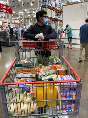 Frisco, TX / USA - 2 Eylül 2020: Costco 'da alışveriş arabasıyla alışveriş maskesini tutan Hintli adam