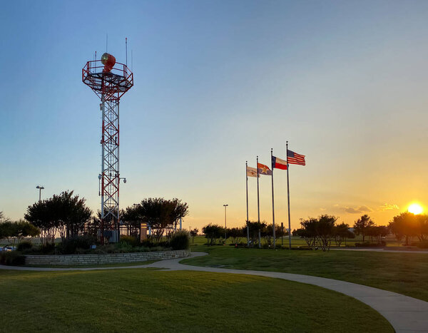 A sunset view of control tower transmission and american and texas flags in DFW Founders' Plaza in Texas