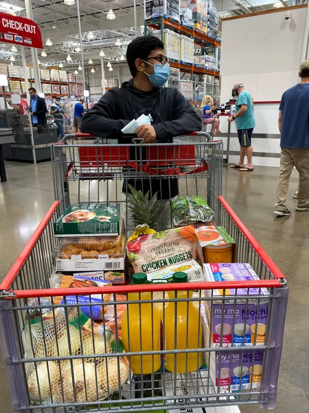 Frisco, TX / USA - 2 Eylül 2020: Costco 'da alışveriş arabasıyla alışveriş maskesini tutan Hintli adam