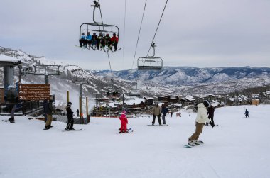 Colorado 'daki Aspen Kar Kütlesi Kayak Tesisi' nde ekspres asansörde ve kayak alanında oturan kayakçılar.