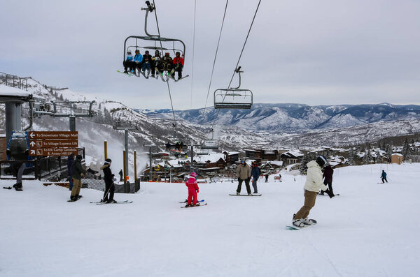 Skiers sitting on the express lift and skiing on the snow ground in Aspen Snowmass Ski Resort in Colorado