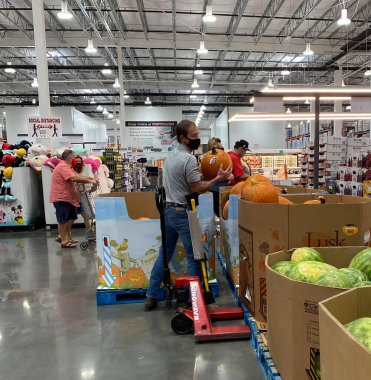 McKinney, TX / USA - 20 Eylül 2020: Costco personeli maske takıyor ve balkabaklarını dolduruyor