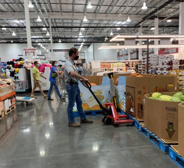 McKinney, TX / USA - 20 Eylül 2020: Costco personeli maske takıyor ve palet kamyonunun yanındaki balkabaklarını dolduruyor