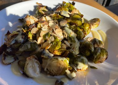 Beyaz bir porselen tabakta bademli kömürleşmiş Brüksel lahanasının yakın görüntüsü