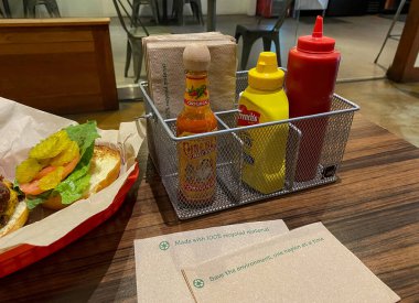 Fast food restoranının yemek masasına soslu ve hamburgerli çevre dostu peçete.