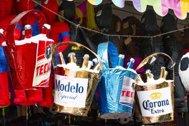 TIJUANA, BAJA CALIFORNIA/MEXICO - JUNE 20, 2018:  Pinatas shaped as buckets of beer hang in an outdoor market. clipart