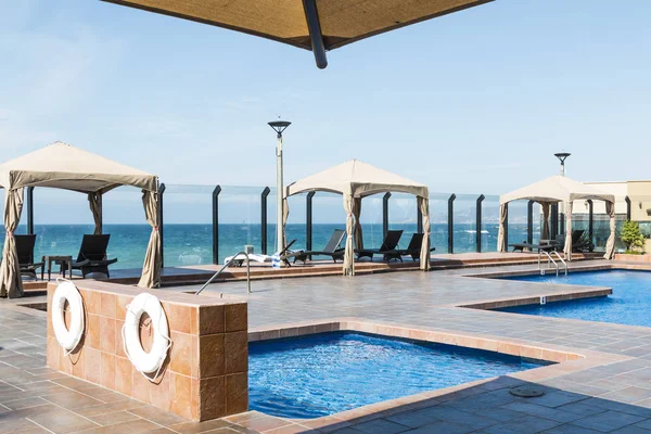 The edge of a cafe umbrella, cabanas, and pool at a resort near the ocean in Ensenada, Mexico.