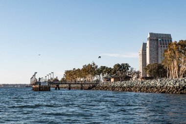 İnsanlar balık Embarcadero Marina Park Güney, iskeleye yerel otel San Diego liman astar manzaralı.  