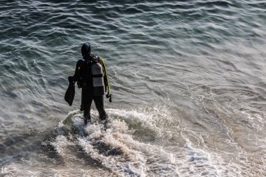 Dalgıç kıyafetli bir adam okyanusa giriyor..