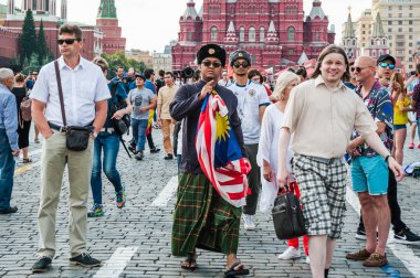 Moskova, Rusya - 29 Haziran 2018: 2018 Dünya Kupası. Ulusal giysiler ve Rus şapka kulak kapakları Malezya bayrağı ile Malezya Turizm kırmızı kare üzerinde yürüyor