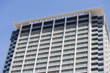 Tokyo, Japonya, 4 Kasım 2023: Yüksek bir ofis binasının modern mimarisi açık mavi gökyüzüne karşı