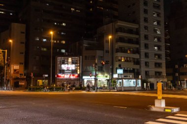 Tokyo, Japonya, 4 Kasım 2023: Yayalar ve bakkallarla aydınlatılmış sokak manzarası