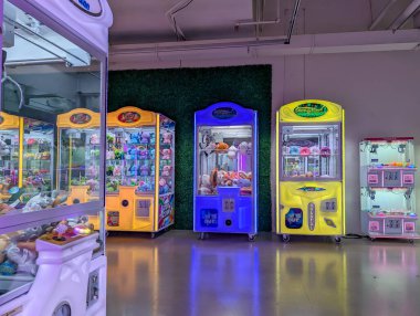 Quebec, Kanada, 05 Temmuz 2025: Parlak ışıklı pençe makineleri davetkar bir şekilde bekleyen renkli peluş oyuncaklarla dolu