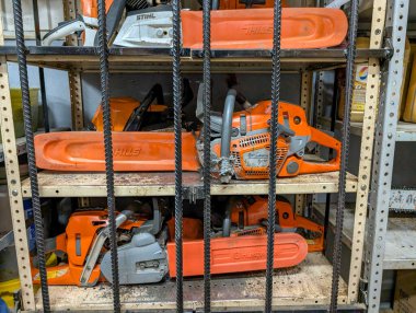 Kanada, 28 Temmuz 2025: Birçok turuncu testere güvenli bir şekilde raflardaki metal parmaklıkların arkasında saklanıyor