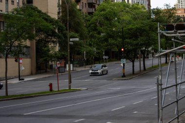 Quebec, Kanada, 05 Temmuz 2025: Tek bir beyaz araba ve kırmızı trafik ışığı ile sessiz kavşak