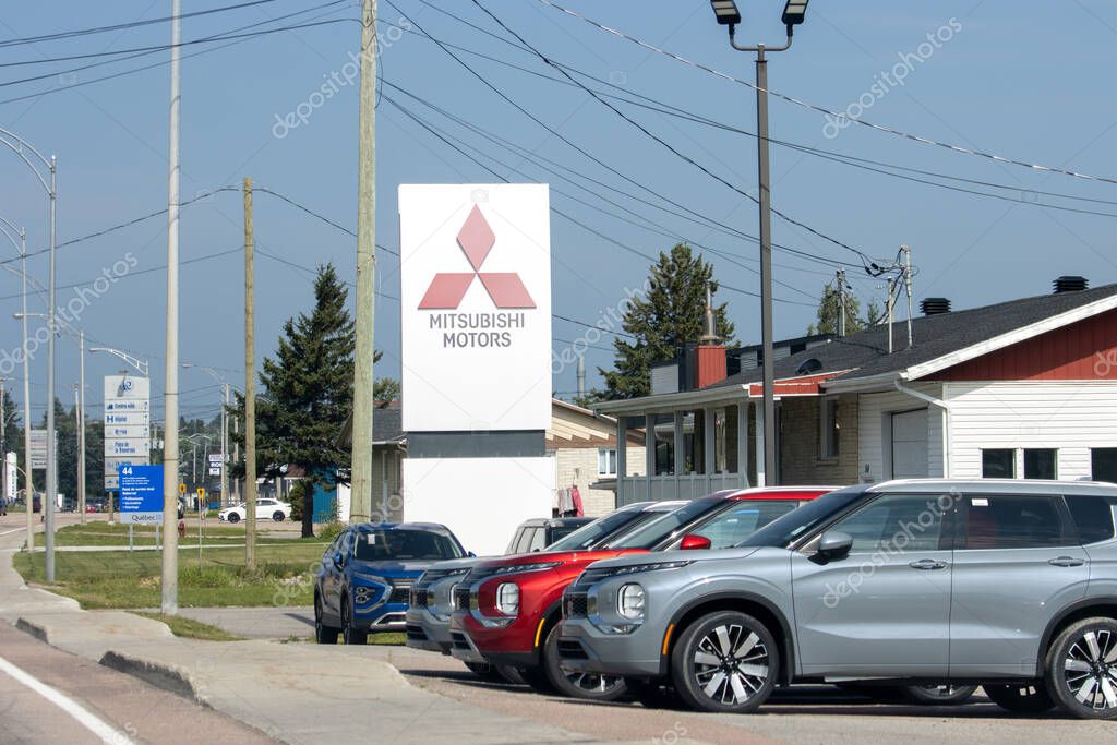 Canada, 09 August 2025 : Modern cars parked outside Mitsubishi Motors dealership under clear sky.