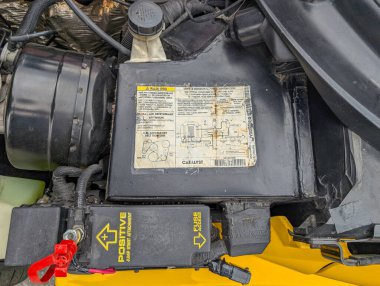 Kanada, 23 Ağustos 2025: Pozitif pil terminali, sigorta erişimi ve yıpranmış motor bölümü bilgi etiketi görünür