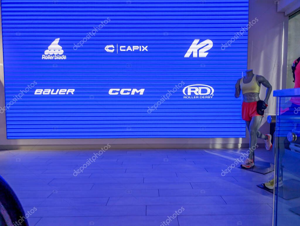 Quebec, Canada, 05 July 2025 : Mannequin with athletic clothing stands before sports brand logo display background