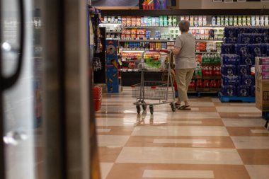 Kanada, 25 Temmuz 2025: Süpermarket içecek reyonunda tek başına alışveriş yapan yaşlı kadın
