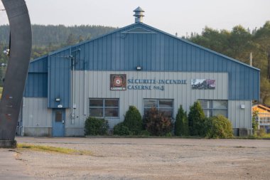 Kanada, 10 Ağustos 2025: Ağaçları, pencereleri ve acil servis işaretli mavi itfaiye binası