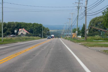 Kanada, 09 Ağustos 2025: Trafik, elektrik hatları, uzak ev ve mavi gökyüzü olan düz kırsal yol