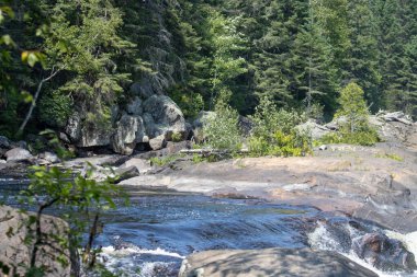 Kanada, 11 Ağustos 2025: Nehir, kayalar ve ağaçlar sakin yabanda uyum içinde harmanlandılar.