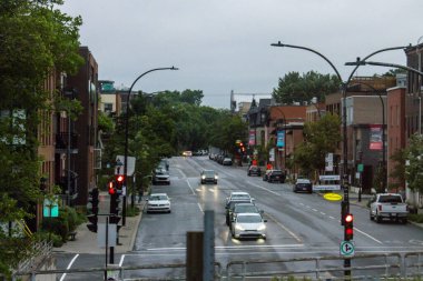Quebec, Kanada, 08 Temmuz 2025: Arabalar, binalar, trafik ışıkları, ağaçlarla dolu yağmurlu şehir sokak sahnesi