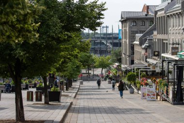 Kanada, 05 Temmuz 2025: Ağaçları, restoranları, yayaları, tarihi binaları ve köprüsü olan güneşli kentsel cadde