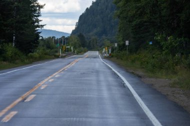 Kanada, 25 Ağustos 2025: Dağlı ve bulutlu gökyüzü olan ıssız kırsal yol