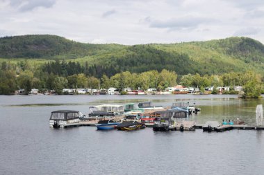 Kanada, 07 Eylül 2025: Yeşil orman geçmişi olan sakin bir göle yanaşan tekneler