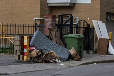 Quebec, Kanada, 05 Temmuz 2025: Şehrin köşesindeki kaldırımda çöp kutusuna dayanan atılmış yatak