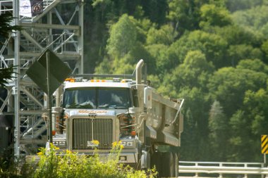 Kanada, 25 Ağustos 2025: Orman yeşili arka planda metal yapının yanına park edilmiş büyük bir kamyon