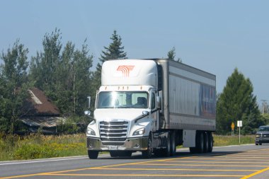 Kanada, 09 Ağustos 2025: Beyaz kargo kamyonu arka planda ağaçlarla otoyolda ilerliyor