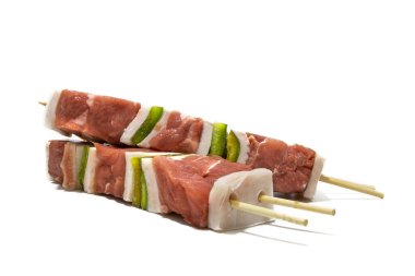 Beyaz arka planda soyutlanmış çiğ et ve biber şişleri. Genellikle bir şiş, soğan, biber, mantar vb ile karıştırılmış et veya balık parçalarından oluşur..