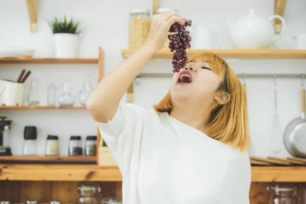 Aasialainen Kaunis Nainen Syö Rypäleitä Kotonaan Keittiössä Onnellinen Kaunis Aasialainen — kuvapankkivalokuva
