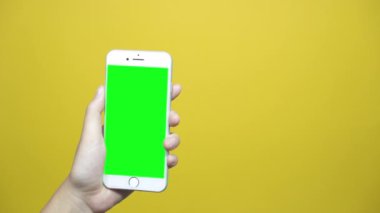 Sarı tablo zemin üzerine yeşil ekranlı akıllı telefon kullanan kadın. Dokunmatik ekranda dokunarak kaydırma sayfaları, Erkek eller.