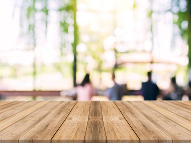 Ahşap tahta boş masa üstü bulanık arkaplan. Kahve dükkanının arka planındaki bulanıklık üzerine perspektif kahverengi ahşap masa - montaj ürünleri görüntüleme veya tasarım anahtar görsel düzeni için kullanılabilir.
