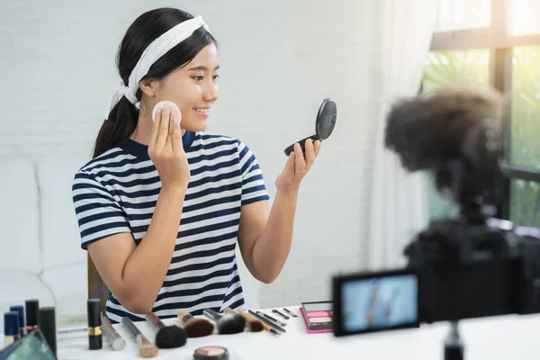 Beauty blogger present beauty cosmetics while sitting in front camera for recording video. Beautiful woman use powder while review make up tutorial broadcast live video to social network by internet.