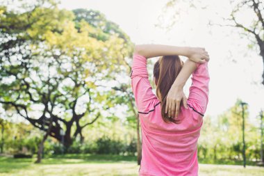 Asyalı genç kadın önce sabah egzersiz ve yoga altında sıcak ışık sabah parkta uzanan vücut ısın. Parkta egzersiz sağlıklı genç Asyalı kadın. Kadın egzersiz açık kavramı.