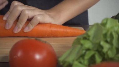 Yavaş hareket - sağlıklı yemek yapma ve mutfakta kesme tahtası üzerinde havuç doğrama kadının yakın.