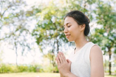 Genç Asyalı kadın yoga açık havada sakin olun ve iç barış keşfetmek için yoga uygulamak ise derin derin düşünür. Yoga ve meditasyon sağlık için iyi faydaları vardır. Yoga spor ve sağlıklı yaşam konsepti.