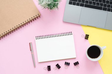 Yaratıcı düz fotoğraf çalışma masası yatıyordu. Üstten Görünüm ofis büro dizüstü bilgisayar, boş boş defter ve kahve fincanı pastel renk arka plan üzerinde. Kopya alanı, düz yatıyordu fotoğraf ile Üstten Görünüm.