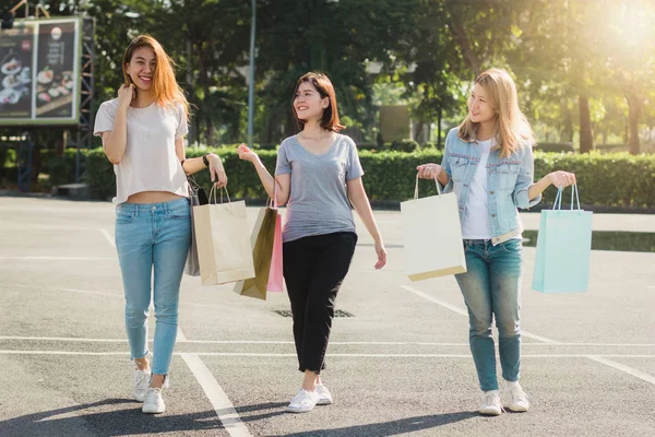 Grup genç Asyalı kadın açık bir pazarda alışveriş torbaları ellerinde ile alışveriş. Genç kadın sıcak güneş ışığı altında alışveriş torbasında marifetlerini göster. Grup açık alışveriş kavramı.