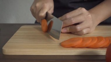Yavaş hareket - sağlıklı yemek yapma ve mutfakta kesme tahtası üzerinde havuç doğrama kadının yakın.