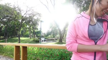 Yavaş hareket - Asyalı güzel kadın fitness kıyafetler içinde kullanıyorsanız bir smartwatch müzik, dinlemek için parkta çalıştırdıktan sonra Evet. Çekici kadın koşu. 